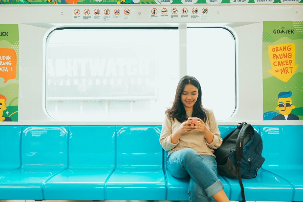 A woman looks at her phone while riding on a subway train
